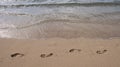 Footprints at golden sand, footsteps. Blue ocean wave on sandy beach. Beach in sunset summer time. Beach landscape