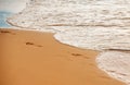 Footprints at golden sand, footsteps. Sea background, nature of tropical summer beach with rays of sun light. Sand beach Royalty Free Stock Photo