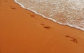 Footprints at golden sand, footsteps. Tropical beach with sea sand on summer vacation. Royalty Free Stock Photo