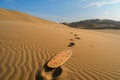 footprints leading to a sandboard in the desert Royalty Free Stock Photo