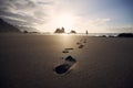 Footprints in sand against silhouette of person Royalty Free Stock Photo