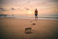 Footprints in sand against silhouette of person Royalty Free Stock Photo