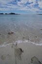 Footprints in sand being erased by an incoming wave on a beach on the Brookes Peninsula