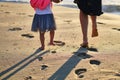 Footprints in sand. Feet of mother and child walk along shore. Summer memories.