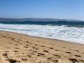 Footprints on sand and container cargo ships on ocean near Valparaiso port