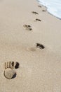 Footprints on sea beach sand with wave foam Royalty Free Stock Photo