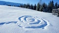 footprints in the snow in the form of a spiral pattern on a snowy slope of a mountain meadow with clear snow