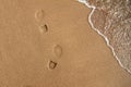 Footprints of walking man s shoes on yellow sand near sea surf, copy space Royalty Free Stock Photo