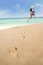 Footprints and woman running at beach Royalty Free Stock Photo