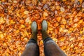 Foots Of Female Gardener.Rubber boots on fall background.Garden with autumn leaves. Woman in rain boots walking in grass.High