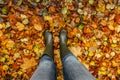 Foots Of Female Gardener.Rubber boots on fall background.Garden with autumn leaves. Woman in rain boots walking in