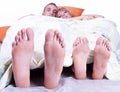 Foots of young couple lying in bed