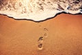 Footsteps foot prints on the beach sand and sea wave at sunrise Royalty Free Stock Photo