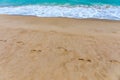 Footsteps in the sand. Footprints in the sand beach. Footprints in the sand against a sea wave. Footprints on a sunny day with