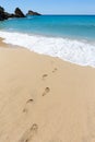 Footsteps in sandy beach leading to blue sea at coast