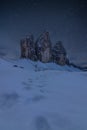 Footsteps in the snow in front of Tre Cime di Lavaredo, UNESCO heritage site in the Italian Dolomites, on a starry night Royalty Free Stock Photo