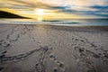 Footsteps tracks in sand on beach with sunrise or sunset. Royalty Free Stock Photo