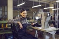 Smiling female shoemaker sitting at workplace looking at camera portrait