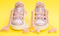 Footwear for girls or women decorated with pearl beads. Pair of pale pink female sneakers with velvet ribbons. Childrens