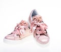 Footwear for girls and women decorated with pearl beads. Pair of pale pink female sneakers with velvet ribbons. Trendy