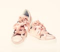 Footwear for girls and women decorated with pearl beads. Pair of pale pink female sneakers with velvet ribbons. Trendy