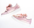Footwear for girls and women decorated with pearl beads. Trendy sneakers concept. Pair of pale pink female sneakers with