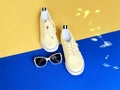 Footwear for women yellow sneakers sunglasses for relaxation time on blue and yellow background