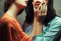 Forbidden love concept. Portrait of two gorgeous girlfriends in blue and orange retro dresses making love in hotel room. Tender Royalty Free Stock Photo
