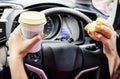 forbidden and perilous with close-up of woman's hand, holding burger and coffee, While driving Royalty Free Stock Photo