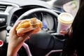 forbidden and perilous with close-up of woman\'s hand, holding burger and coffee, While driving Royalty Free Stock Photo