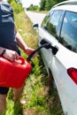 Force majeure, problems on the road, self-refuelling. The driver fills up the empty tank of the car from a red canister on the Royalty Free Stock Photo