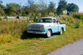 Ford F100 antique pickup truck parked in a farm field along the roadside blue