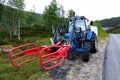 Ford tractor with trailer, used as a hay bales loader and hauler stands at a roadside