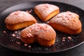 Fore cupcakes in heart with powdered sugar on a black plate.