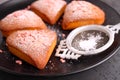 Fore cupcakes in heart with powdered sugar on a black plate.