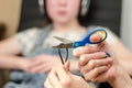 In the foreground, female hands are cutting the headphone cord with scissors, in the background is a girl in headphones Royalty Free Stock Photo