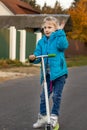 foreground. a girl with white hair and in a blue jacket riding a scooter. and moshet us hand