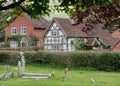 In foreground, graves in grounds of St Mary the Virgin Church in Turville in The Chilterns, with characterful houses behind.