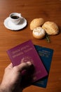 In the foreground, Italian and Brazilian passport, in the background and blurred a small cup of coffee and three loaves of bread w