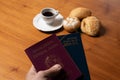 In the foreground, Italian and Brazilian passport, in the background and blurred a small cup of coffee and three loaves of bread w