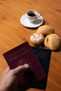 In the foreground, Italian and Brazilian passport, in the background and blurred a small cup of coffee and three loaves of bread w