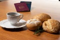 In the foreground, Italian and Brazilian passport, in the background and blurred a small cup of coffee and three loaves of bread w