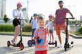 In the foreground, a little boy holds a skate in his hands and gives a thumbs up Royalty Free Stock Photo