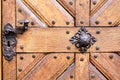 Foreground of old wooden door with iron handle.