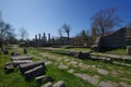 In the foreground a pavement of a Roman road with some ruins, in the background you can see some columns of the Basilica. 