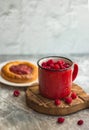 In the foreground is a red mug with garden raspberries, in the background a cheesecake with berry filling, light background, defoc
