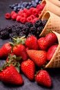 In the foreground, variety of fresh berries in ice cream cones Royalty Free Stock Photo