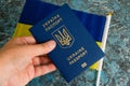 A foreign passport of a Ukrainian in his hand and a flag of Ukraine on a dark background. Concept of Ukrainian Royalty Free Stock Photo