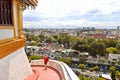 Foreign tourist with red dress descends the stairs of the temple of the golden mount with city scape in background in Bangkok Thai