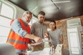 Foreman or achitect shows house, office or store design plans to a young couple